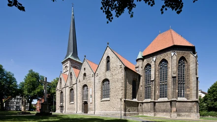 Pfarrkirche St. Michael Die Pfarrkirche St. Michael, ein gotisches Bauwerk, steht unter blauem Himmel mit umliegenden Bäumen.