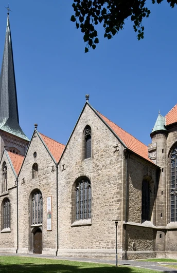 Pfarrkirche St. Michael Die Pfarrkirche St. Michael, ein gotisches Bauwerk, steht unter blauem Himmel mit umliegenden Bäumen.