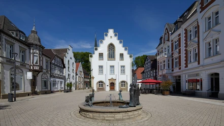 Rathaus von Brakel mit Giebel-Spitzdach, umgeben von historischen Gebäuden, zentraler Brunnen.