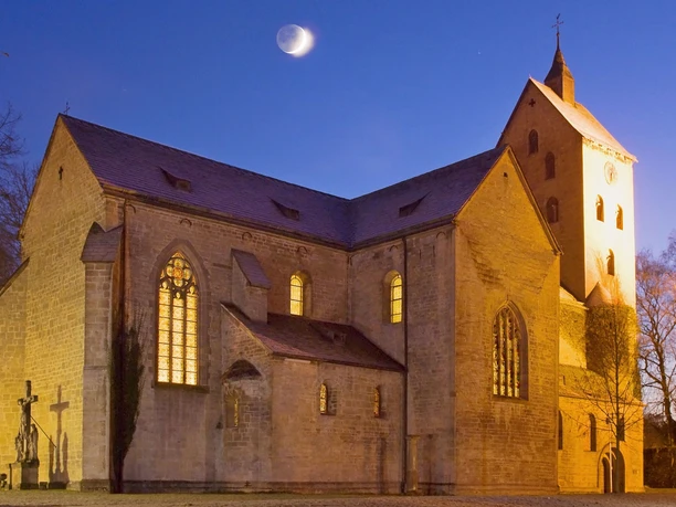 Die Klosterkirche St. Peter und Paul in Gehrden bei Nacht, erleuchtet unter einem klaren Mondhimmel.