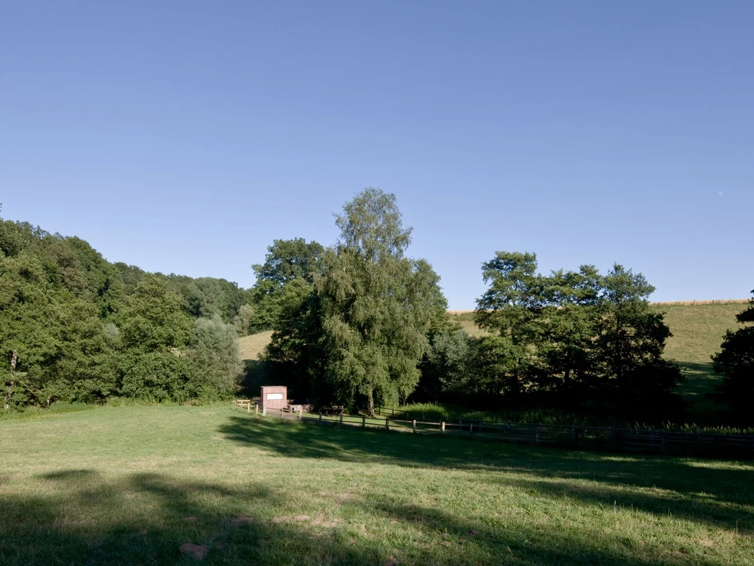 Metbrunnen in Schmechten Geräumige Lichtung vor einem kleinen, umgeben von dichten Wäldern und sanften Hügeln.