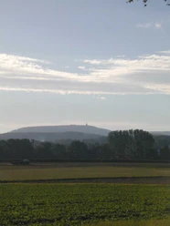 Blick zum Hermannsdenkmal Blick über ein weites Feld hin zum Hermannsdenkmal am Horizont, vor bewaldetem Hügelzug.