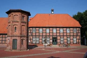 Packhaus Thedinghausen Historisches Fachwerkgebäude mit rotem Ziegeldach und Turmanbau auf einem gepflasterten Platz.