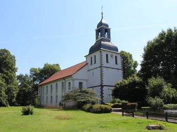 Kirche Blender Weißgetünchte Kirche mit rotem Dach und Zwiebelturm steht umgeben von grünen Bäumen unter blauem Himmel.The whitewashed church with a red roof and onion dome is surrounded by green trees under a blue sky.Den hvidkalkede kirke med rødt tag og løgkuppel er omgivet af grønne træer under en blå himmel.De witgekalkte kerk met een rood dak en uienkoepel wordt omringd door groene bomen onder een blauwe hemel.