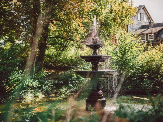 Brunnen im Stiftsgarten Ein großer Springbrunnen im Einbecker Stiftsgarten im Sommer.