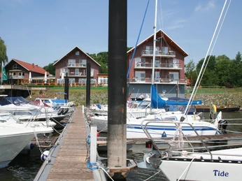 Uesener Hafen Achim Mehrere Boote liegen an Holzstegen vor einem Backsteingebäude mit Balkonen im Uesener Hafen Achim.