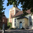 Kirche Uchte Eine historische Kirche mit gelber Fassade, großem Turm und mehreren Rundbogenfenstern.