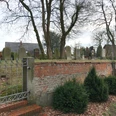 Älterer jüdischer Friedhof mit historischen Grabsteinen, umgeben von Bäumen und einer Ziegelmauer.