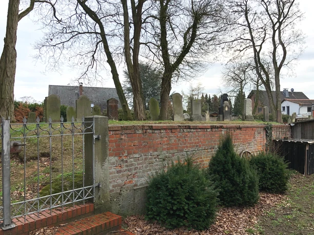 Jüdischer Friedhof Älterer jüdischer Friedhof mit historischen Grabsteinen, umgeben von Bäumen und einer Ziegelmauer.