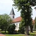 Die Kirche Martfeld in Bruchhausen-Vilsen ist umgeben von Bäumen, mit einem markanten Glockenturm.