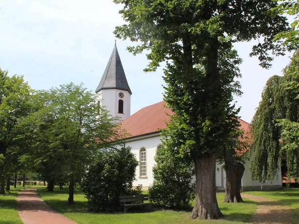 Bruchhausen-Vilsen Kirche Martfeld Die Kirche Martfeld in Bruchhausen-Vilsen ist umgeben von Bäumen, mit einem markanten Glockenturm.