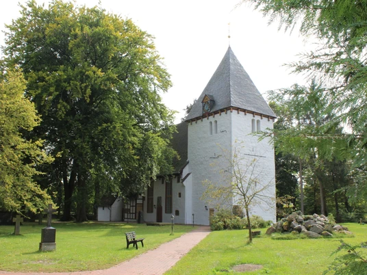 Die Danielskirche in Lavelsloh liegt umgeben von Natur, mit einem markanten Turm und gepflegtem Grün.
