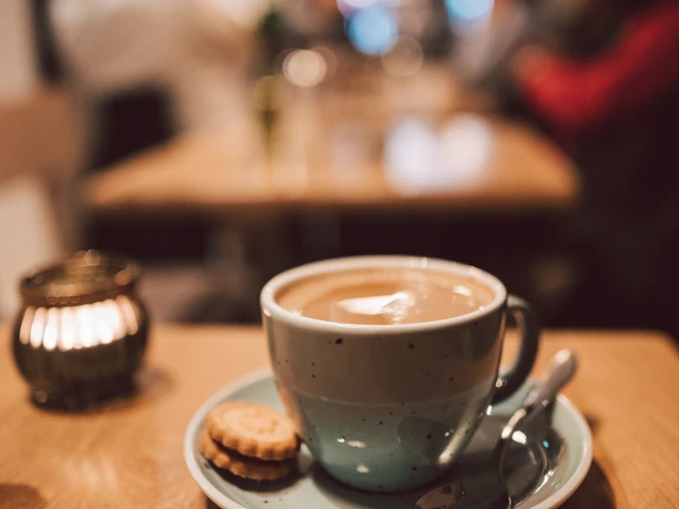 Filled coffee cup with cookie and spoon.