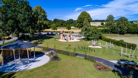 Spielplatz im Ludowinengarten Bökendorf, umgeben von grüner Landschaft und blühenden Beeten.