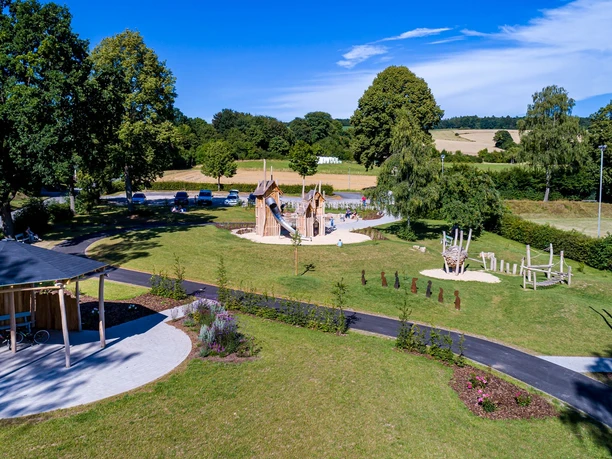Spielplatz im Ludowinengarten Bökendorf, umgeben von grüner Landschaft und blühenden Beeten.