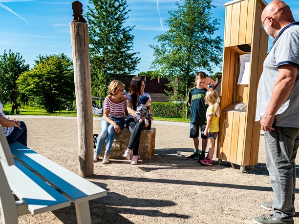 Seniorin und Familie ruhen sich im Ludowinengarten Bökendorf bei strahlendem Sonnenschein aus.