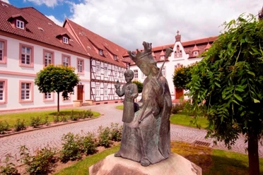Kloster auf der Brede, Brakel Klostergelände mit Bronzeskulptur einer jungen Frau und eines Kindes, umgeben von historischen Gebäuden.