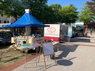 Markt Werlte.jpg Menschen schlendern über den Wochenmarkt in Werlte mit bunten Ständen und Essenswagen im Freien.
