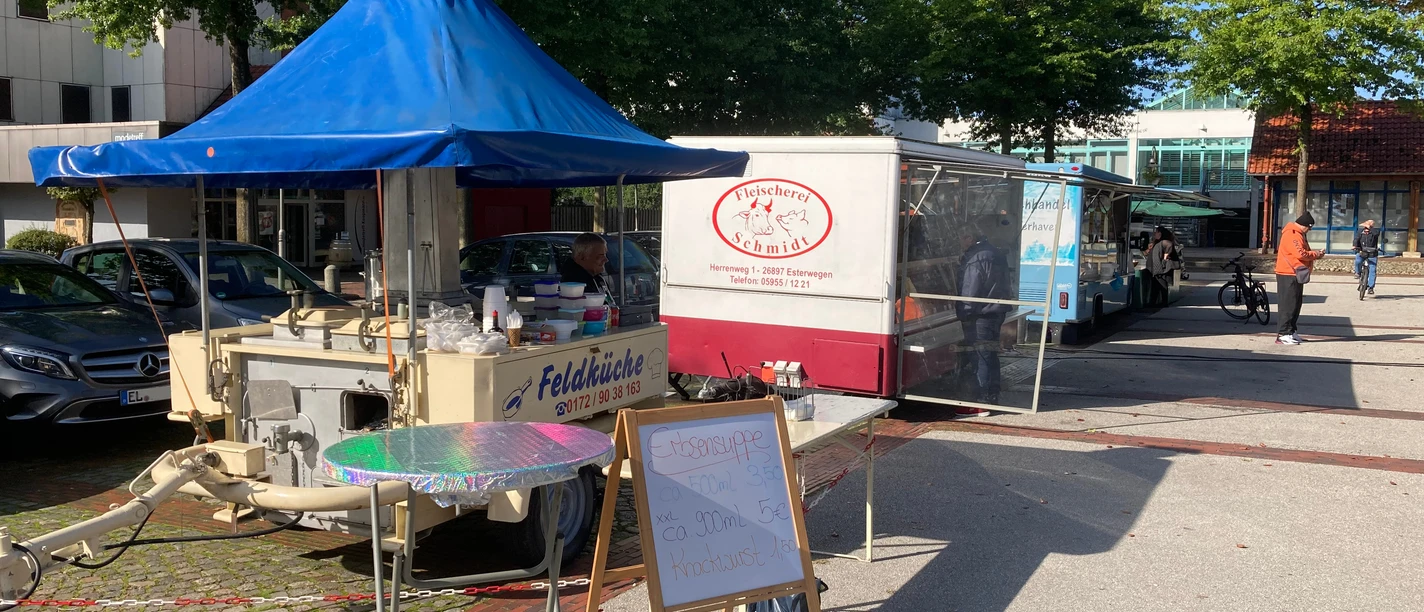 Markt Werlte.jpg Menschen schlendern über den Wochenmarkt in Werlte mit bunten Ständen und Essenswagen im Freien.