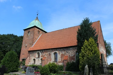 Kirche Bühren Historische Backsteinkirche mit markantem Turm und begrüntem Umfeld unter blauem Himmel.