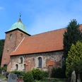 Kirche Bühren Historische Backsteinkirche mit markantem Turm und begrüntem Umfeld unter blauem Himmel.