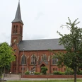 Kirche Thedinghausen Backsteinkirche mit hohem Spitzturm und grünen Bäumen, die majestätisch in einem ruhigen Umfeld steht.