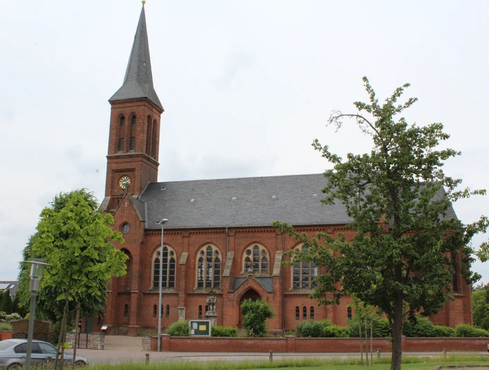 Kirche Thedinghausen Backsteinkirche mit hohem Spitzturm und grünen Bäumen, die majestätisch in einem ruhigen Umfeld steht.