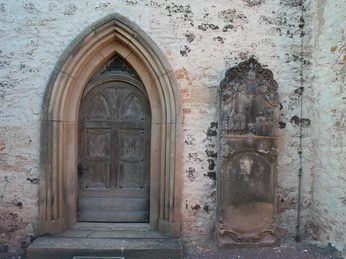 St. Aegidien-Kirche Rodewald Eingang zur St. Aegidien-Kirche Rodewald mit gotischem Bogen, flankiert von einer historischen Gedenktafel.