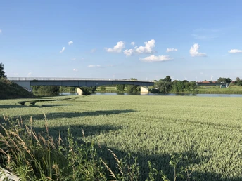 Die Weserbrücke in Landesbergen überspannt den Fluss, umgeben von weiten Feldern und blauem Himmel.