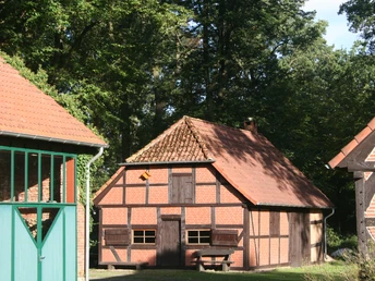 Estorfer Scheunenviertel Historische Fachwerkscheune mit rotem Ziegeldach, umrahmt von Bäumen im Estorfer Scheunenviertel.