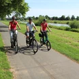 Radfahrer an der Weser Drei Radfahrer genießen eine sonnige Fahrt auf einem Radweg entlang der grünen Weserlandschaft.