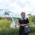 Eine Frau in historischer Tracht steht vor einer blauen Brücke an einem Flussufer in Nienburg.