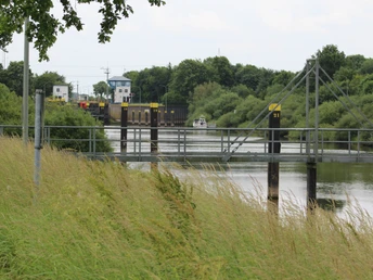 Schleusenkanal in Langwedel mit grünem Ufer und Schiff, bei einer Überführung, im Sommer.