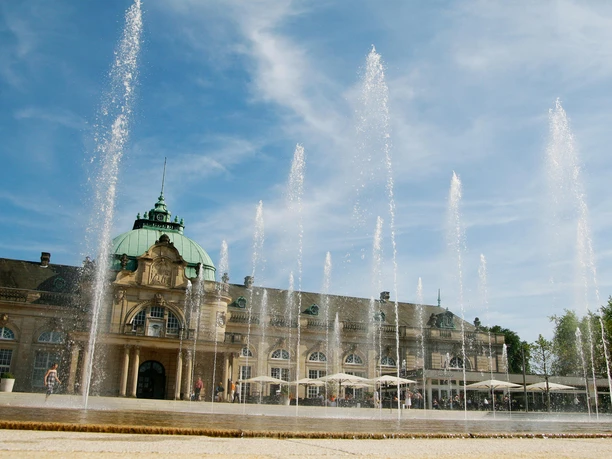 Leander Außenbereich (c) GOP Variete.jpg Auf dem Bild ist der Außenbereich des Leanders zu sehen, mit Blick auf das Kaiserpalais. Die Fontänen sind eingeschaltet, und das Wasser spritzt in die Luft.