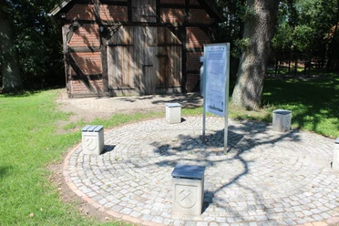 Kalibergbau Hülsen Ein traditionelles Kalibergbaumuseum mit Infotafel, umrandet von grünen Wiesen und Schattenspender.