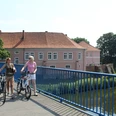 Radfahrer am Grafenschloss Hoya Zwei Radfahrer auf einer Brücke vor dem historischen Grafenschloss Hoya an einem sonnigen Tag.