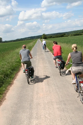 Radfahrer in Langwedel Radfahrer auf einem schmalen Weg entlang grüner Felder, blauer Himmel mit weißen Wolken oben.