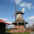 Feldmühle Martfeld: Historische Windmühle aus Backstein und Holz in ländlicher Umgebung unter blauem Himmel.