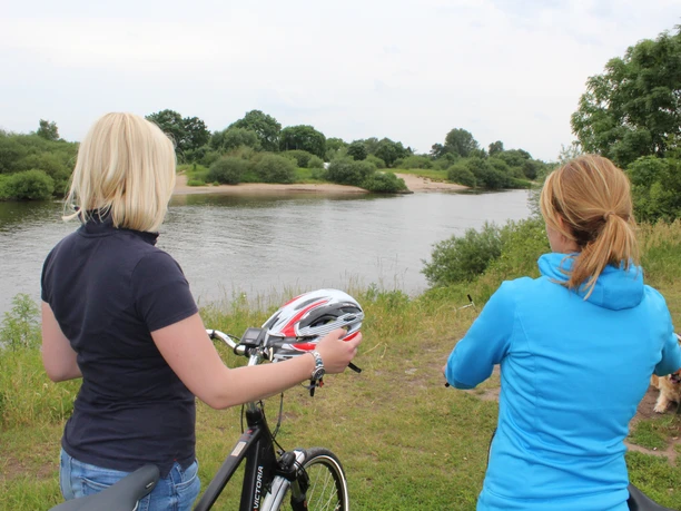 Radler an der Weser Zwei Frauen stehen mit Fahrrädern am Weserufer, blicken auf den ruhigen Fluss und die Natur.