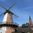Windmühle Lahde Windmühle in Lahde mit markantem Backsteinbau und grauen Flügeln, umgeben von historischen Häusern.