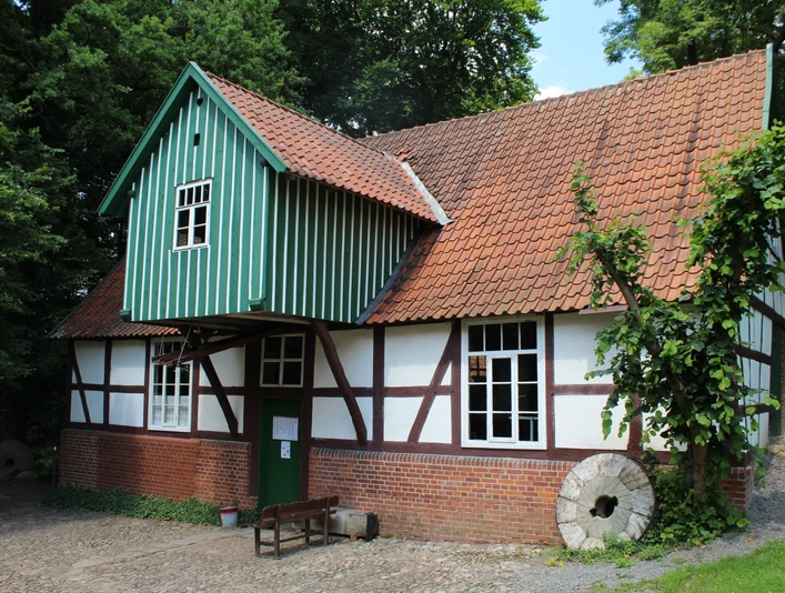 Plaggen Mühle Döhren Fachwerkhaus der Plaggen Mühle Döhren mit backsteinrotem Dach, umrahmt von dichtem Grün der Natur.