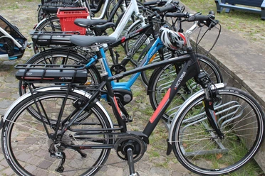 Radfahren Mehrere Fahrräder stehen geordnet auf einem gepflasterten Parkplatz, bereit zur Nutzung.