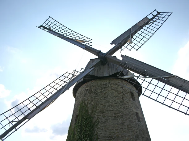 Historic Wegholm windmill with four sails against a blue sky, imposing and well preserved.