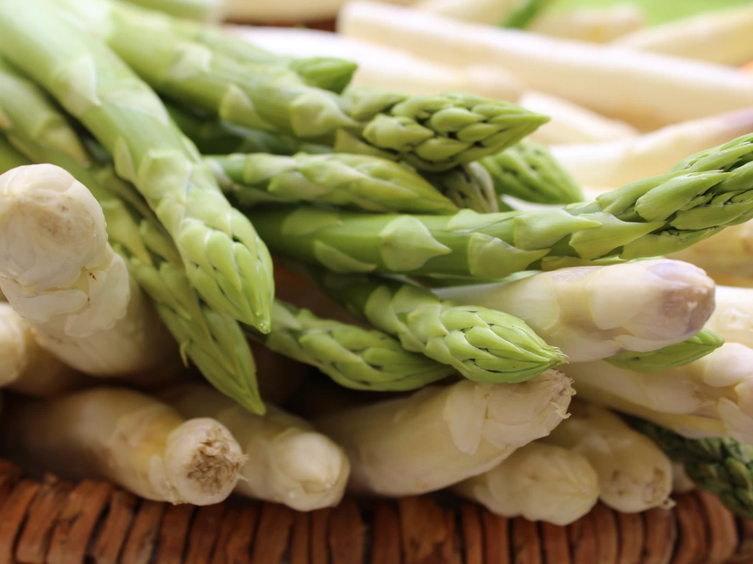 Frischer grüner und weißer Spargel in Nahaufnahme, liegend auf einem hölzernen Untergrund.