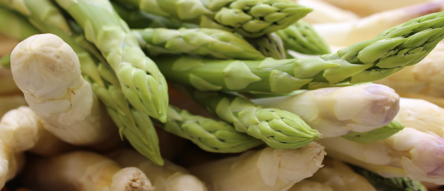 Spargelstangen Frischer grüner und weißer Spargel in Nahaufnahme, liegend auf einem hölzernen Untergrund.