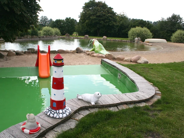 Naturfreibad Pennigsehl Naturfreibad Pennigsehl mit rutschender Kinderrutsche, Leuchtturm-Skulpturen und grünem Rasen.