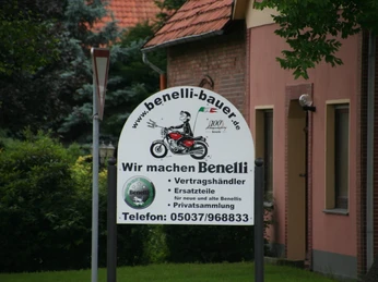 Benelli Museum Ankündigung der Benelli-Motorräder, darauf ein stilisierter Motorradfahrer, umgeben von Bäumen.