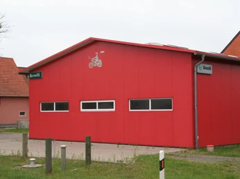 Benelli Museum Ein rotes Gebäude mit dem Benelli-Logo beherbergt das Benelli Museum in einer ländlichen Umgebung.