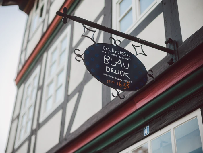 Beschilderung „Einbecker Blaudruck 1638" an einem Fachwerkhaus.