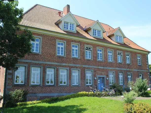 Amtshaus Westen mit Heimatstube Backsteinbau mit hohem Dach, symmetrischer Fensterreihe und grüner Umgebung, Fahrräder vor dem Gebäude.